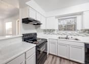 Thumbnail 108 of 142 - A kitchen with white cabinets and a black stove top oven.