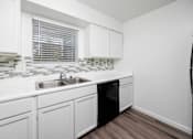 Thumbnail 109 of 142 - A kitchen with white cabinets and a black dishwasher.