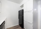 Thumbnail 110 of 142 - A black refrigerator is in a kitchen with white cabinets.
