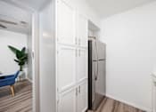 Thumbnail 73 of 142 - A kitchen with a refrigerator, a chair, and a plant.
