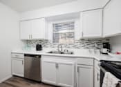 Thumbnail 76 of 142 - A white kitchen with a dishwasher, sink, and oven.