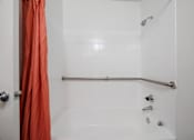 Thumbnail 81 of 142 - A white bathroom with a shower and orange curtain.