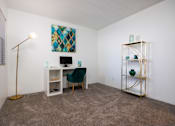 Thumbnail 85 of 142 - A room with a desk, chair, and a painting on the wall.