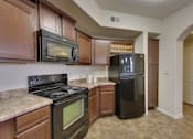 Thumbnail 36 of 39 - A kitchen with a black stove and microwave.