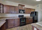Thumbnail 35 of 39 - A kitchen with black appliances and brown cabinets.