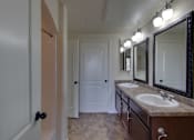 Thumbnail 38 of 39 - A bathroom with a sink, mirrors and a door.