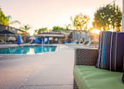 Thumbnail 21 of 27 - A poolside setting with a green couch and striped pillow at Nola 624 Apartments, West Covina, California