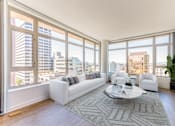 Thumbnail 30 of 104 - A living room with a large window overlooking a cityscape at The Grand Apartments, Oakland