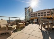 Thumbnail 6 of 104 - A sunny day on a rooftop patio with wooden furniture at The Grand Apartments, California