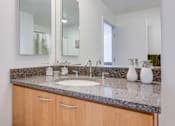 Thumbnail 39 of 104 - A bathroom with a sink, mirror, and cabinets at The Grand Apartments, Oakland 94612