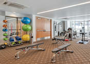 Thumbnail 97 of 104 - A gym with a variety of equipment including weights and exercise balls at The Grand Apartments, California