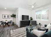 Thumbnail 42 of 87 - A living room with a grey couch, a glass table, a television, and a ceiling fan.