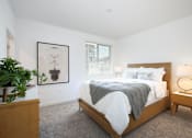 Thumbnail 46 of 87 - Apartments in West Sacramento, CA, with In-Unit Washer and Dryer - The Strand - Bedroom with Carpeted Flooring, Bed, Wooden Nightstands with Lamps, Dresser, White Walls, and Window.