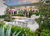 Thumbnail 38 of 85 - A patio with tables and chairs surrounded by greenery.