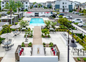 Thumbnail 24 of 85 - A pool surrounded by a patio with chairs and a table.