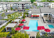 Thumbnail 23 of 85 - A pool surrounded by red umbrellas and lounge chairs.