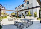 Thumbnail 36 of 85 - A patio with a table and chairs is surrounded by a white building.
