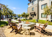 Thumbnail 45 of 85 - A patio with chairs and a firepit in front of a building.