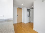Thumbnail 61 of 104 - A room with a wooden floor and a white wall with a door at The Grand Apartments, Oakland
