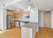 Thumbnail 46 of 104 - A kitchen with wooden floors and stainless steel appliances at The Grand Apartments, Oakland