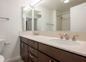 Thumbnail 83 of 104 - A bathroom with a white sink and brown drawers at The Grand Apartments, California