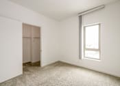 Thumbnail 86 of 104 - A room with a carpeted floor, a window, and a closet at The Grand Apartments, Oakland, CA