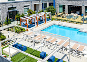Thumbnail 110 of 137 - A pool with loungers and a table is surrounded by a fence.