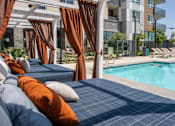 Thumbnail 116 of 137 - A poolside lounge area with orange pillows and curtains.