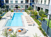 Thumbnail 109 of 137 - A swimming pool surrounded by lounge chairs and umbrellas in a courtyard.
