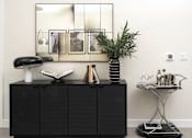 Thumbnail 15 of 137 - A black cabinet with a mirror above it and a small table with a plant on it.