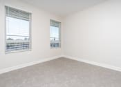 Thumbnail 44 of 137 - A room with two windows and carpeted flooring.