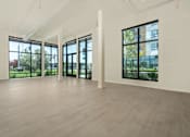 Thumbnail 53 of 137 - A spacious room with large windows and wooden flooring.