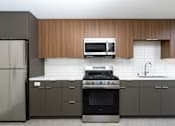 Thumbnail 70 of 137 - A modern kitchen with a refrigerator, oven, microwave, and sink.
