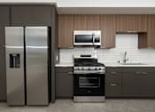 Thumbnail 54 of 137 - A modern kitchen with a stainless steel refrigerator and oven.