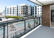 Thumbnail 60 of 137 - A view of a balcony with a pool and apartment buildings in the background.