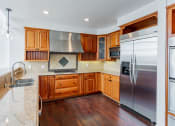 Thumbnail 41 of 44 - a kitchen with wooden cabinets and stainless steel appliances at Vendome Place, San Jose, CA