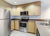 Thumbnail 17 of 51 - Kitchen with Stainless Steel Appliances, Wooden Cabinets, Quartz Countertops, and Hardwood-Style Flooring at Venue, California