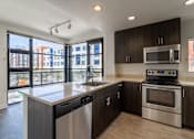 Thumbnail 49 of 51 - A modern kitchen with dark wood cabinets and stainless steel appliances.