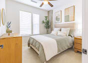 Thumbnail 22 of 34 - Bedroom with Carpeted Flooring, Bed, Nightstand with Lamp, Dresser, Framed Circular Mirror, Ceiling Fan, Wall Art, and Windows at Waterford RiNo, Denver, Colorado