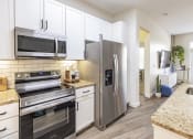 Thumbnail 19 of 34 - Modern Kitchen with Wood-Style Plank Flooring, Stainless Steel Appliances, Granite Countertops, Subway Tile Backsplash, and White Shaker Cabinetry at Waterford RiNo, Denver, Colorado