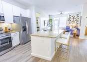 Thumbnail 18 of 34 - a kitchen with stainless steel appliances and an island with two stools at Waterford RiNo, Colorado 80216
