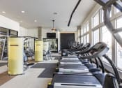 Thumbnail 12 of 34 - a row of treadmills in a gym with large windows at Waterford RiNo, Denver, CO 80216