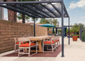 Thumbnail 49 of 52 - Outdoor Dining Area with Long Wooden Table, Chairs with Orange Cushions, Overhead Covering, Potted Plants, and Blue Umbrella. at Westlake Canyon, Thousand Oaks, California