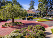 Thumbnail 14 of 81 - Brick paved driveway with tree lined entrance at Woodbend Apartments, Alta Loma, CA