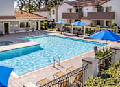 Thumbnail 8 of 81 - Resort style pool with spa and blue umbrellas at Woodbend Apartments, Alta Loma