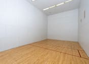 Thumbnail 20 of 81 - Indoor racquetball court with wooden floor at Woodbend Apartments, Alta Loma, CA
