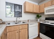 Thumbnail 72 of 81 - Kitchen with oak cabinets and electric stove at Woodbend Apartments, Alta Loma, CA