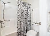 Thumbnail 77 of 81 - Bathroom with patterned shower curtain and tub at Woodbend Apartments, California, 91701