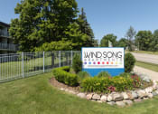 Thumbnail 19 of 20 - a sign for wind song apartments in front of a fence