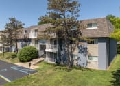 Thumbnail 11 of 20 - an exterior view of a grey apartment building with balconies and trees